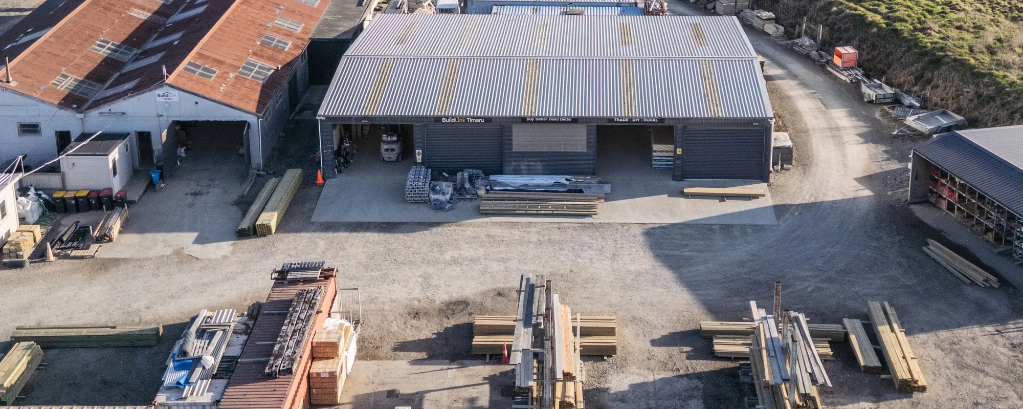 The BuildLink Timaru yard from the air: the main shed with its BuildLink Timaru signage, and stacks of timber in front