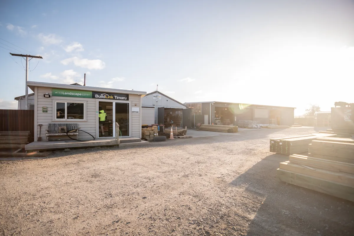 The BuildLink Timaru office in the King Street yard, with the sheds and timber stacks behind it in the late sun