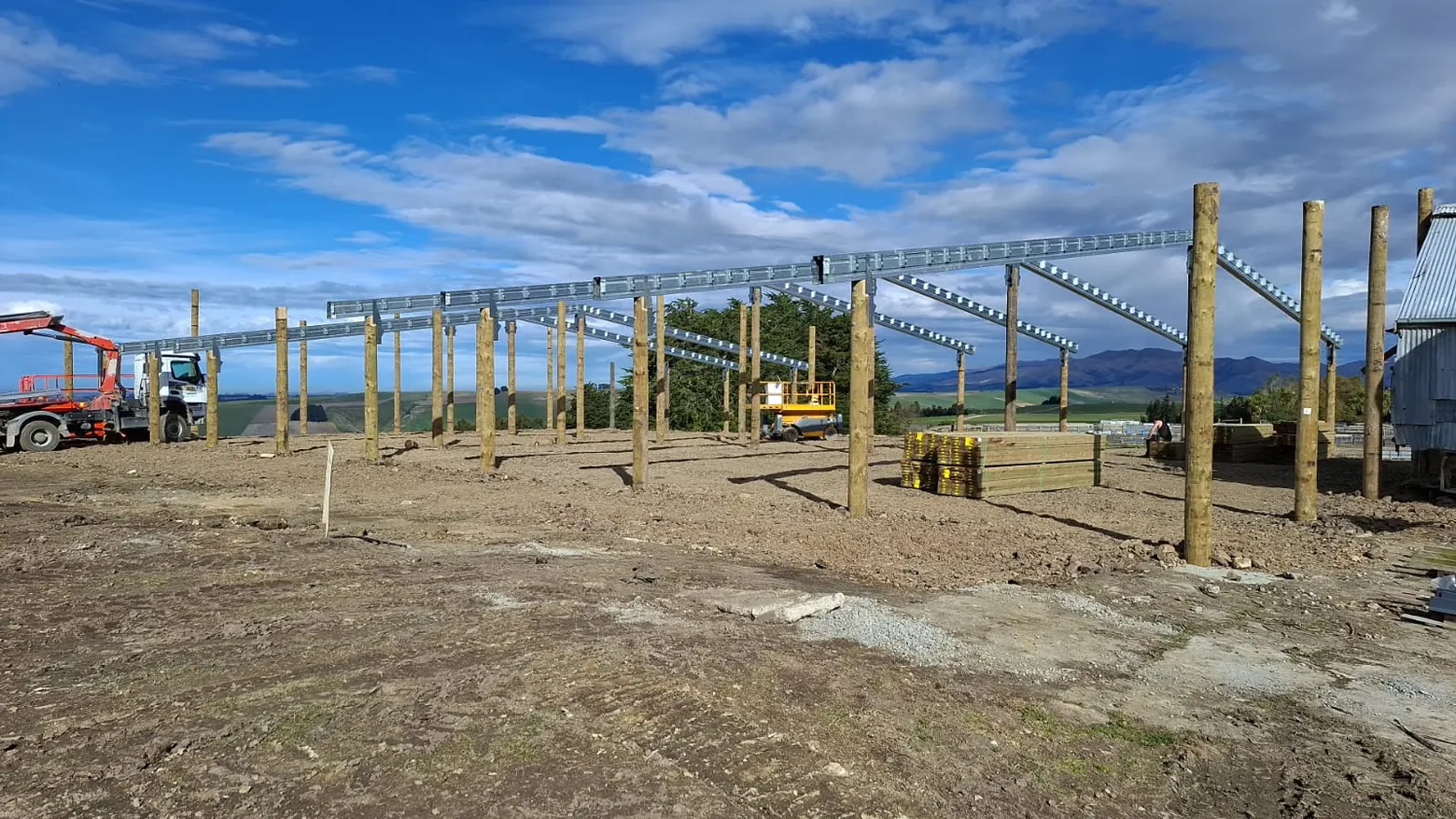 A pole shed going up, poles set and the rafters and purlins on, with the Canterbury hills behind