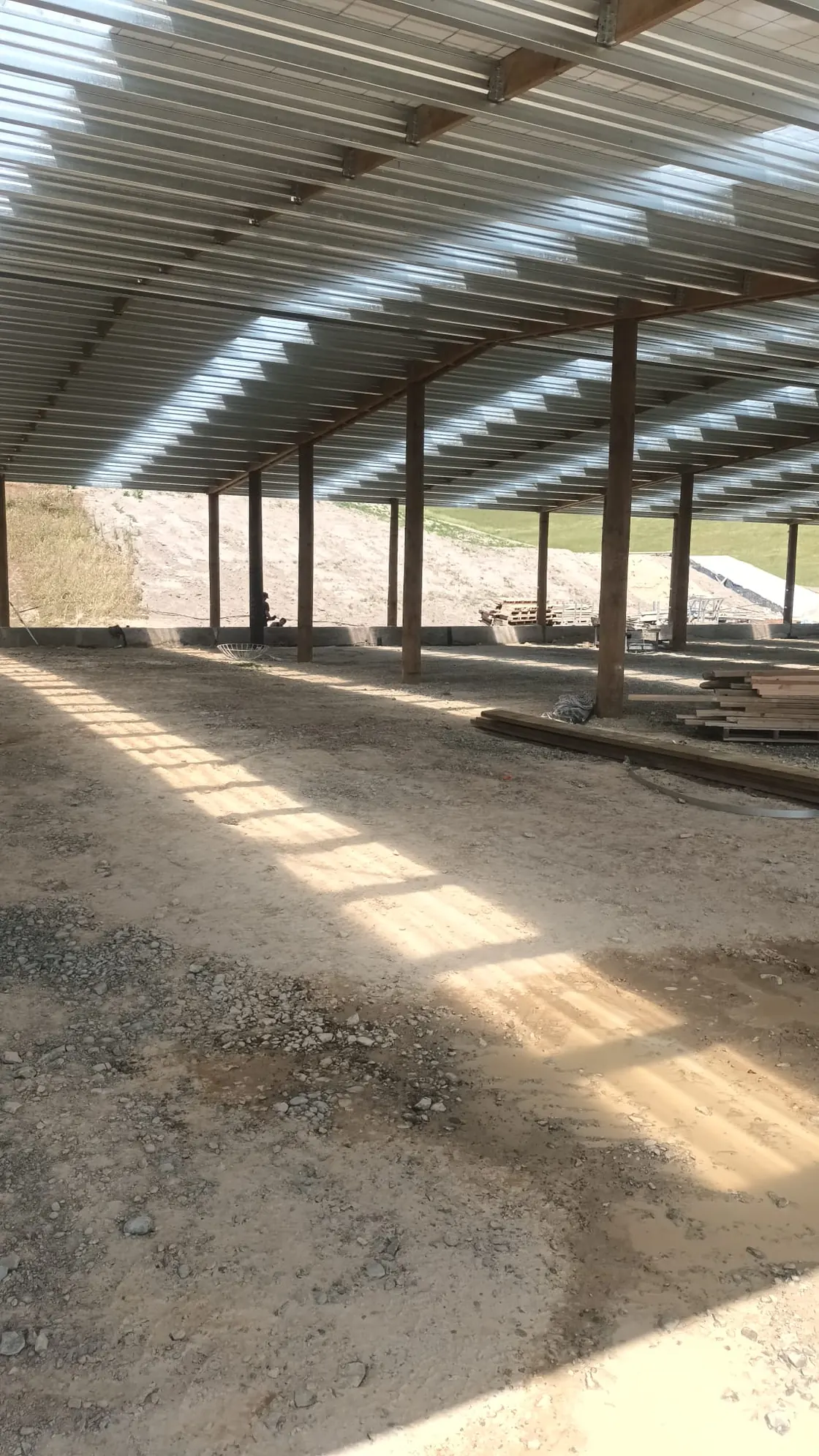 Inside a farm shed under construction, sunlight coming through the clear roof sheets