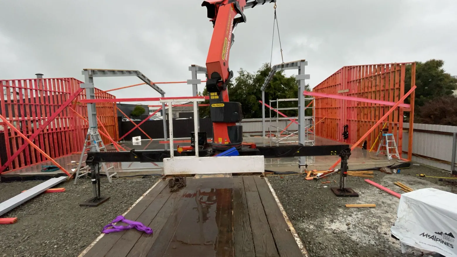 A crane lifting wall panels into place on a shed build